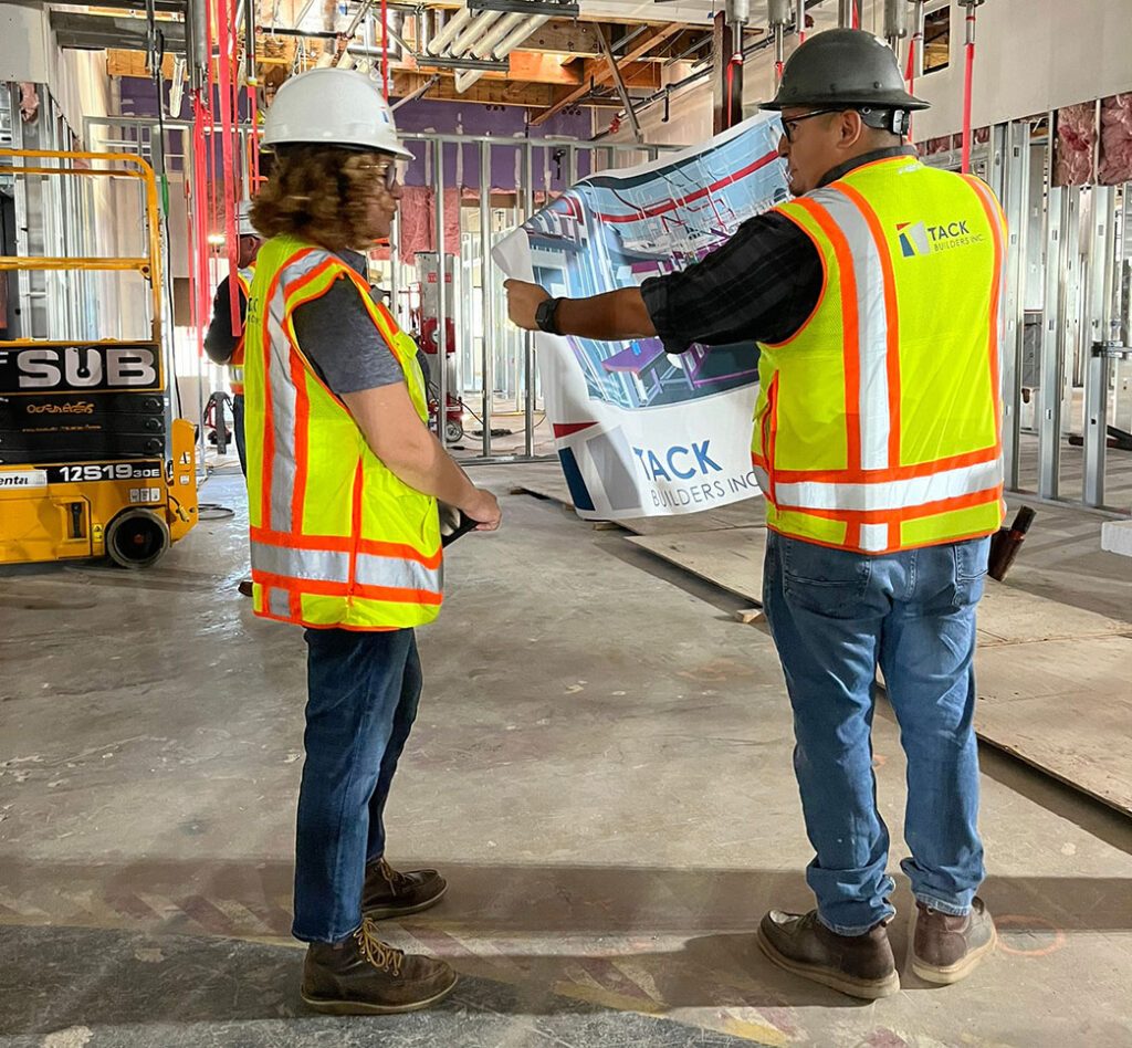 Design-Build Construction Team in Safety Vests Onsite Reviewing Plans